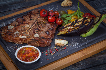  juicy, fried, tender steak with vegetables and sauces on a special stand