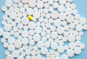 A little yellow-white capsule on white pills background