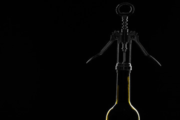 Bottle of wine with corkscrew on the black stone background