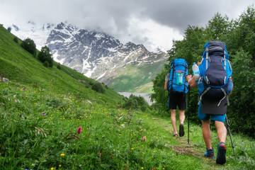 Naklejka na ściany i meble Friends in mountain trek. Backpackers hike on mountains trail. Hiking in highlands. Climbing.