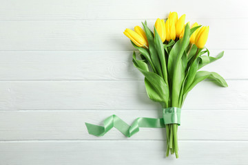 Beautiful yellow tulip flowers and gift box on wooden background. Space for text