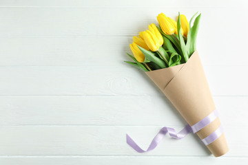 Beautiful bouquet of yellow tulips on wooden background, top view