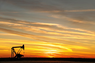 Pump jack in the oil field at sunset