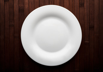 Empty white plate on wooden brown background. - 248518658