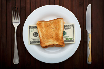 Conceptual photo. Sandwich with one hundred dollar bills. On a white plate. Near fork and knife. Top view. - 248518688