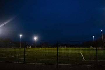 Fototapeta na wymiar Football field at night illuminated by spotlights