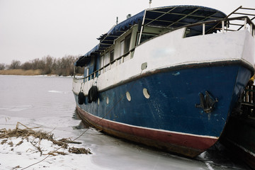 A small old ship is on the pier on the coast in winter