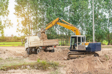 Yellow excavator machine loading soil into a dump truck at construction site
