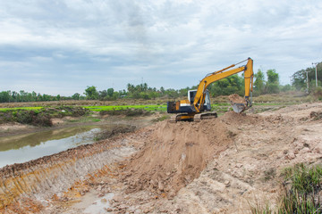 Yellow excavator machine working earth moving works at construction site