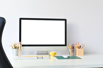 Workspace computer and office supplies on white office desk.