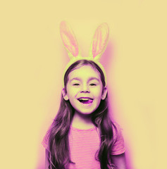 Easter girl portrait. Cute little girl with bunny ears on pink background. Easter child portrait, funny emotions, surprise. Copyspace for text.