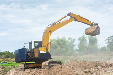 Fototapeta na wymiar Yellow excavator machine working earth moving works at construction site