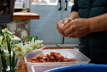 View of male hands preparing fresh shrimps, a basked full of shrimps and some flowers in a vase on the table
