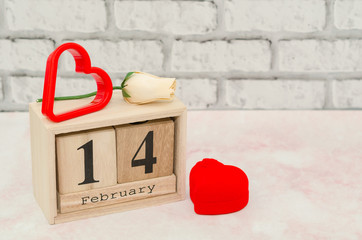 Valentines Day - Calendar date with white rose and heart decoration. Valentines day with wooden block calendar and engagement ring