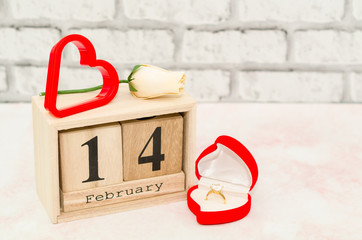 Valentines Day - Calendar date with white rose and heart decoration. Valentines day with wooden block calendar and engagement ring