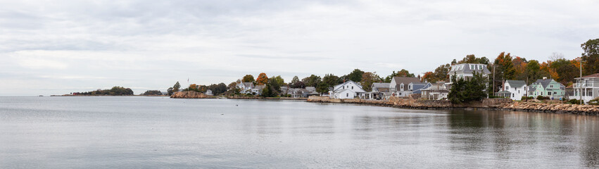 Panoramic view on residential homes on the Rocky Coast during a cloudy morning. Taken on the Atlantic Ocean in New Haven, Connecticut, United States.
