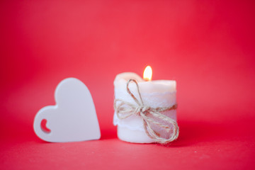 Burning white candle on a red background. Valentine's Day