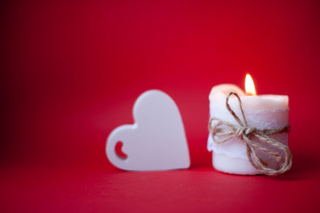 Burning white candle on a red background. Valentine's Day