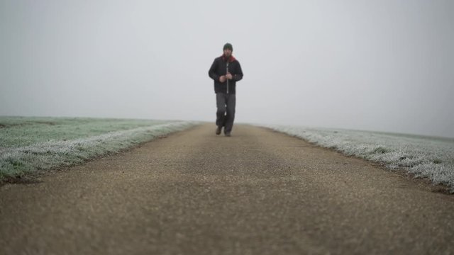 Image of man running on countryside road taken by mist, Heuchlingen, Germany.