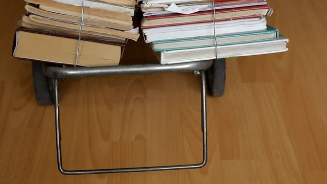 handcart with bundles of books moves on light laminate