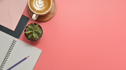 Flat lay, top view office table desk. Workspace with blank clip board, keyboard, office supplies, pencil, green leaf, and coffee cup on pink background