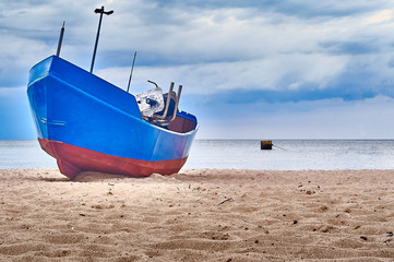 Naklejka na ściany i meble Blue fishing boat sitting on the beach of Rewal, Poland