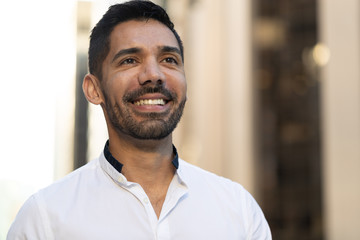 Young Latino Hispanic man in city smile happy face 
