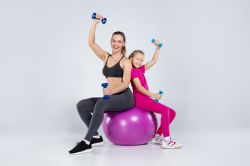Athletic woman and nice girl doing sport exercises
