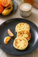Vegetarian breakfast of quark pancakes with honey, fruit and coffee with milk. Rustic style.