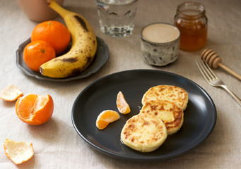 Vegetarian breakfast of quark pancakes with honey, fruit and coffee with milk. Rustic style.