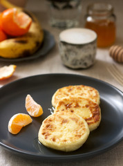 Vegetarian breakfast of quark pancakes with honey, fruit and coffee with milk. Rustic style.
