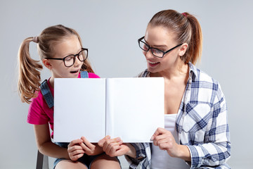 Smiling beautiful woman and her daughter in glasses with book