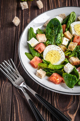 Fresh vegetable salad with tomatoes, spinach, bread crumbs, egg and feta. Healthy food. Dietary dinner or lunch menu. Salad plate on the table.
