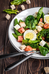 Fresh vegetable salad with tomatoes, spinach, bread crumbs, egg and feta. Healthy food. Dietary dinner or lunch menu. Salad plate on the table.