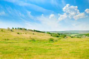 Landscape with hilly field and blue sky.