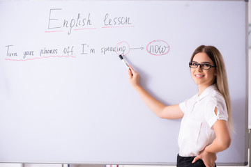 Young female english language teacher standing in front of the b