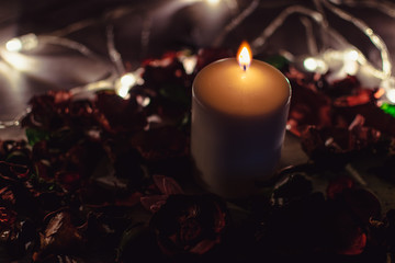 Dark romantic background. Candle decorated with flowers and lights.