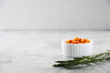 Colorful hot sea buckthorn tea with rosemary and fresh sea buckthorn berries on a grey table. Vitamin drink.