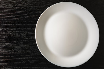 empty white plates on black background, top view
