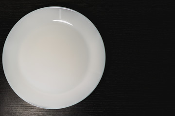 empty white plates on black background, top view
