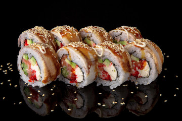 Sushi roll with smoked eel, salmon, tuna, avocado, cucumber, philadelphia cheese, unagi sauce and tobiko on black background. Sushi menu. Japanese food.