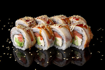 Sushi roll with unagi sauce, smoked eel, salmon, avocado on black background. Sushi menu. Japanese food.