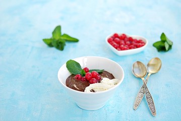 Sweet dessert, chocolate pudding in white portioned saucers on a light blue background. Served with whipped cream and red currant berries. Valentine's Day concept.