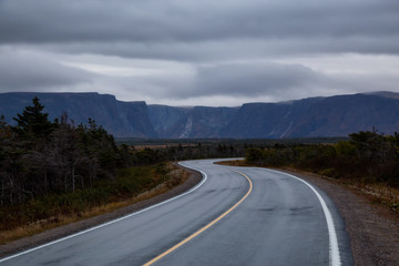 Scenic curvy road in the Canadian Landscape during a cloudy sunset. Taken in Gros Morne National Park, Newfoundland, Canada.