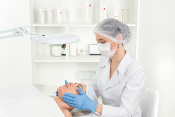 Female beautician doctor with patient in wellness center. Professional cosmetologist make procedure...