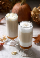 Homemade pumpkin latte in tall glasses and pumpkin on a linen tablecloth. Rustic style.