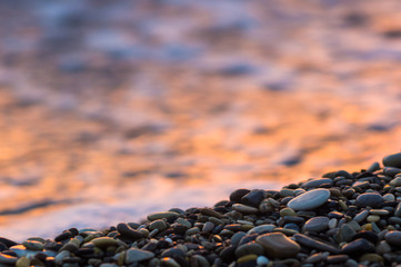 pebble stones on the sea beach, the rolling waves of the sea with foam