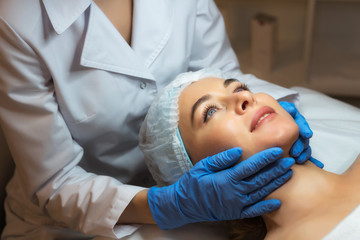 Female beautician doctor with patient in wellness center. Professional cosmetologist make procedure to beautiful girl in cosmetology cabinet or beauty parlor.