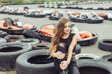 Gorgeous beauty model posing outdoors in street racing  with tires and cars on background. Speed,...