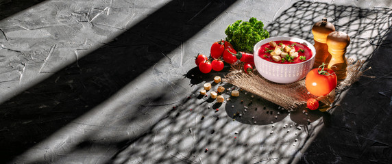 Delicious tomato soup in a ceramic bowl on a dark background with copy space